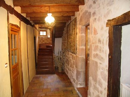 Le-moulin-de-maraval-Cordes-su-ciel-couloir-1 Couloir avec murs en pierre, poutres et escalier authentique menant à l'étage ; sol en tomettes d'origine.