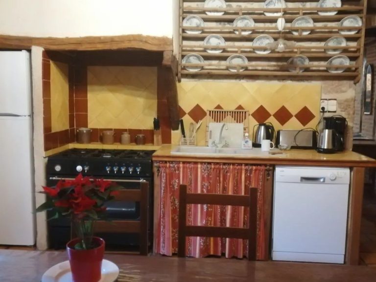 Le-moulin-de-maraval-cuisine-6 Cuisine équipée avec piano de cuisson, lave vaisselle et tous les ustensiles, surmontée d'un vaisselier rustique.