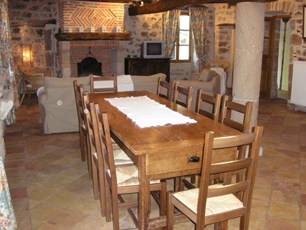 Le-moulin-de-maraval-Cordes-sur-ciel-séjour-4 Salle à manger chaleureuse et spacieuse avec cheminée, murs en pierre et colombages ; sol en tomettes rustiques.